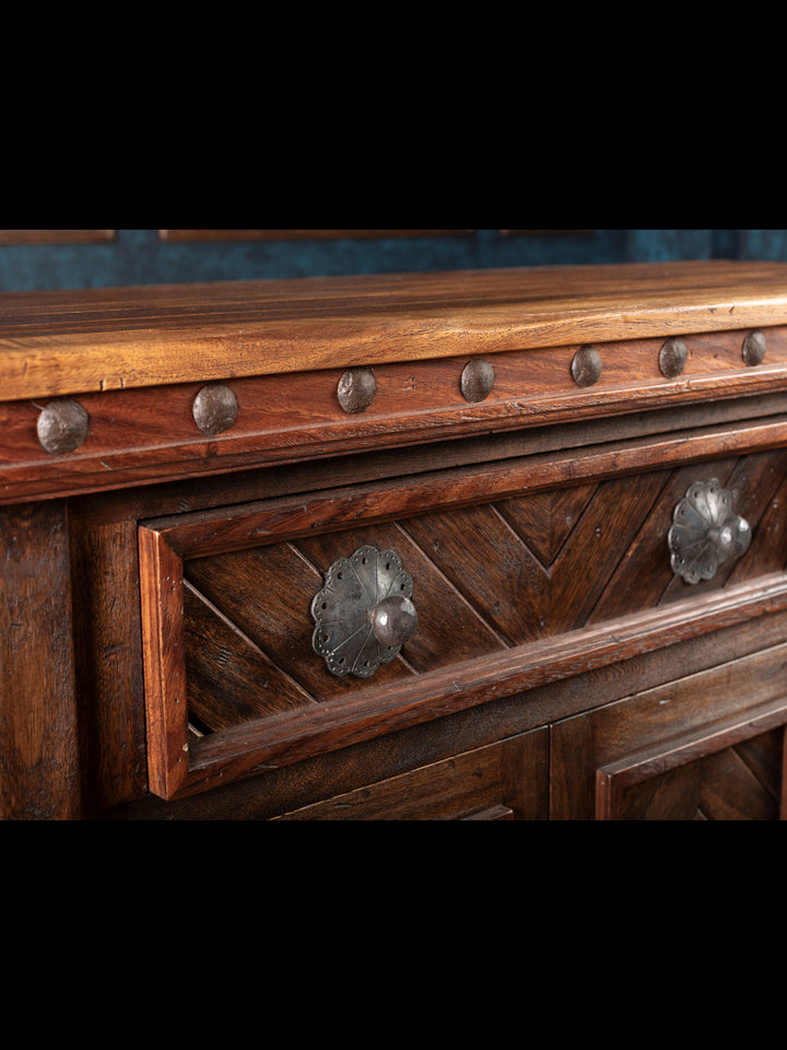 Wooden console with metal studs and decorative handles on a dark background