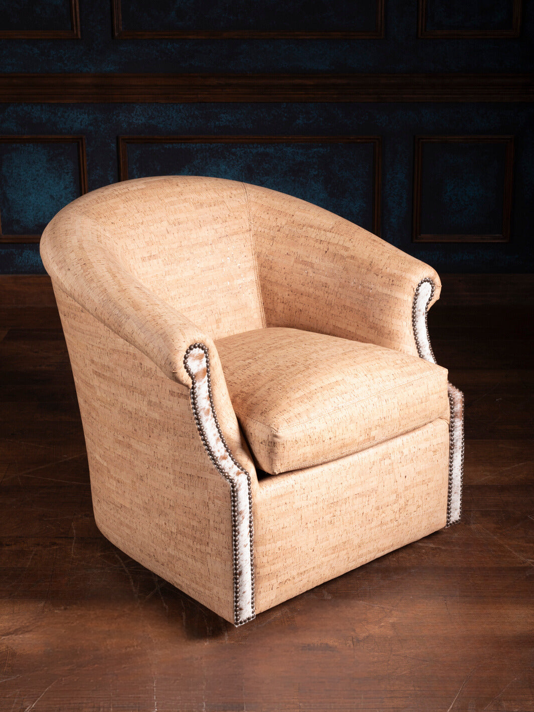 Swivel chair with textured upholstery and decorative nailhead trim running the full arm and back seam
