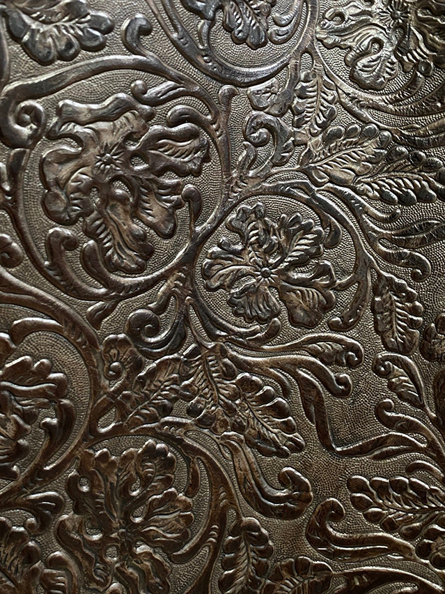 Macro detail of hand-tooled Western leather with deep floral relief