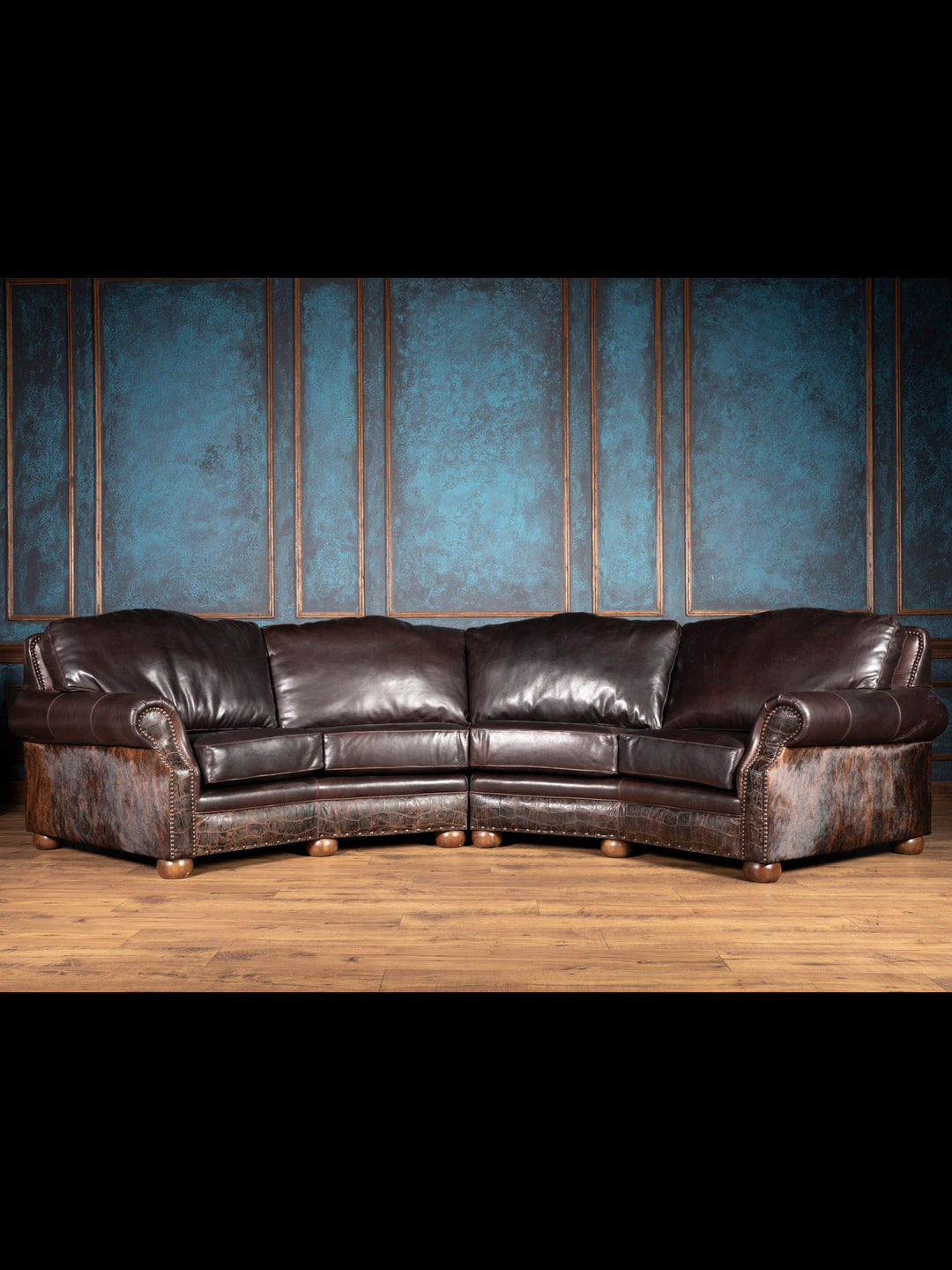 Curved chocolate leather sectional sofa with cowhide and croc accents in rustic living room setting