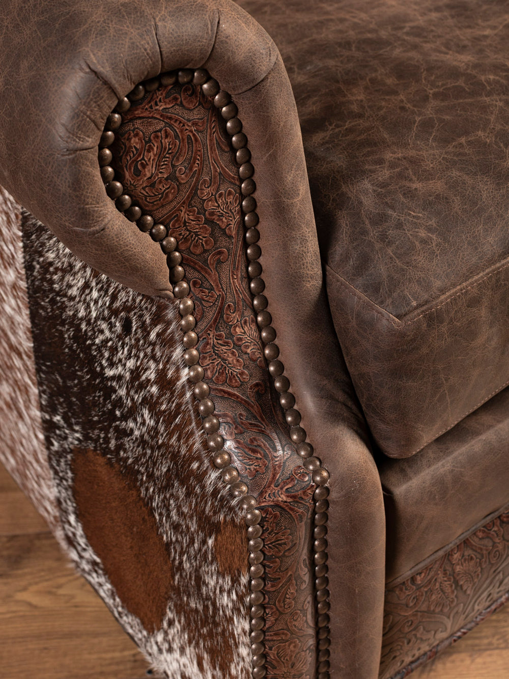 Close-up of a brown leather armchair with intricate stitching and patterns.