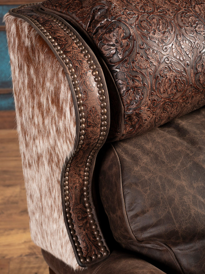 Close up of brown leather recliner showcasing floral accents and gold nailheads