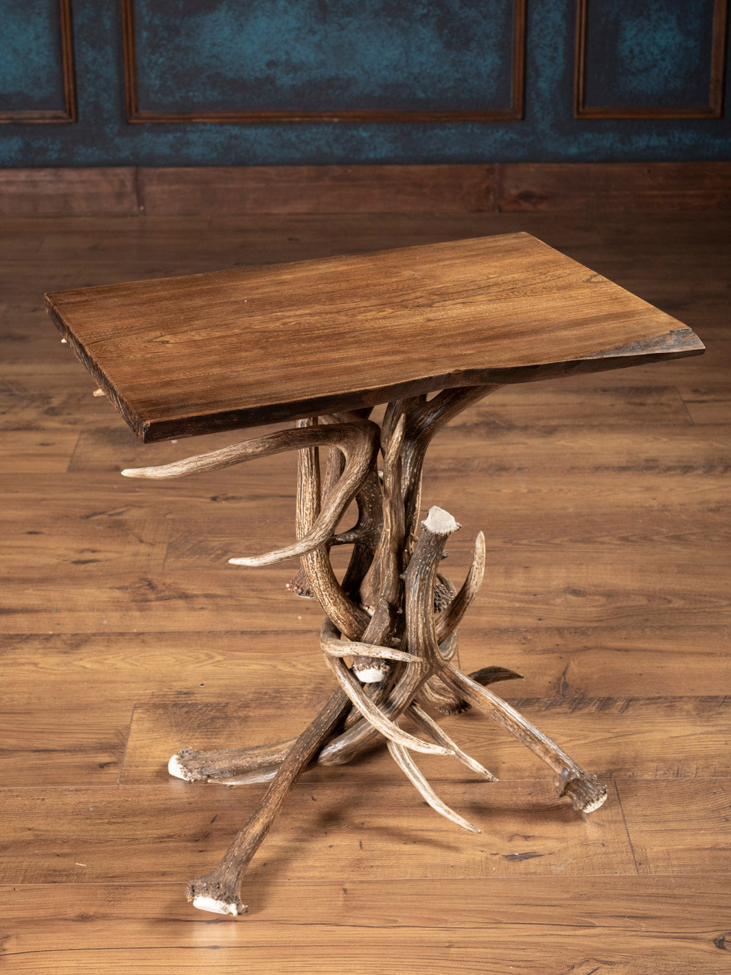 Wooden table with antler legs on a wooden floor against a blue wall.