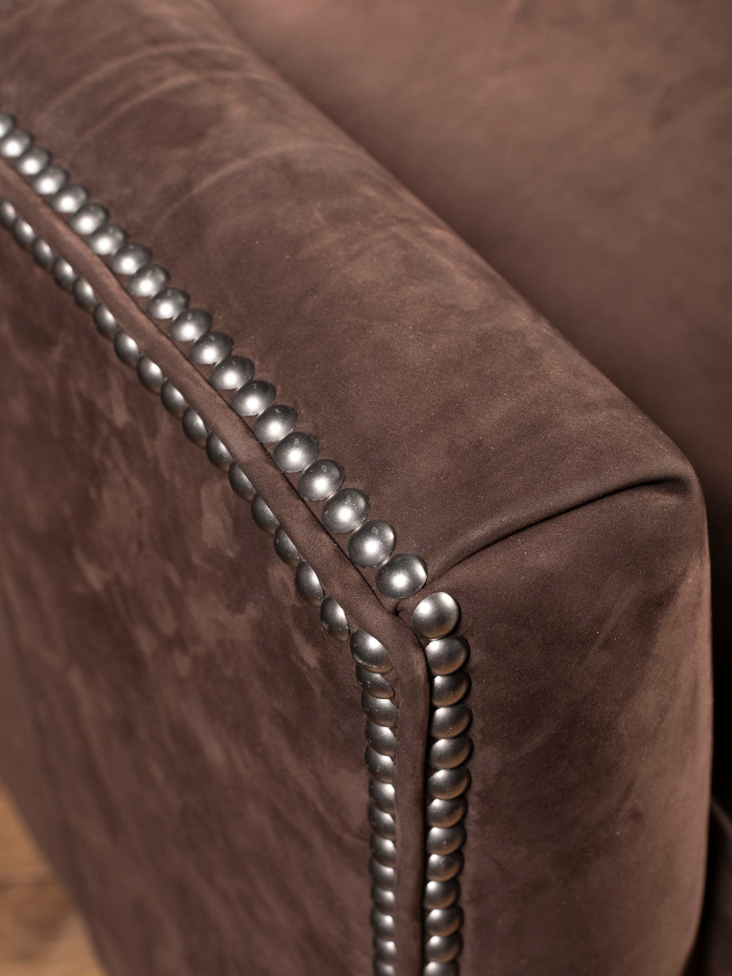 Close up of brown leather recliner arm with silver nailheads