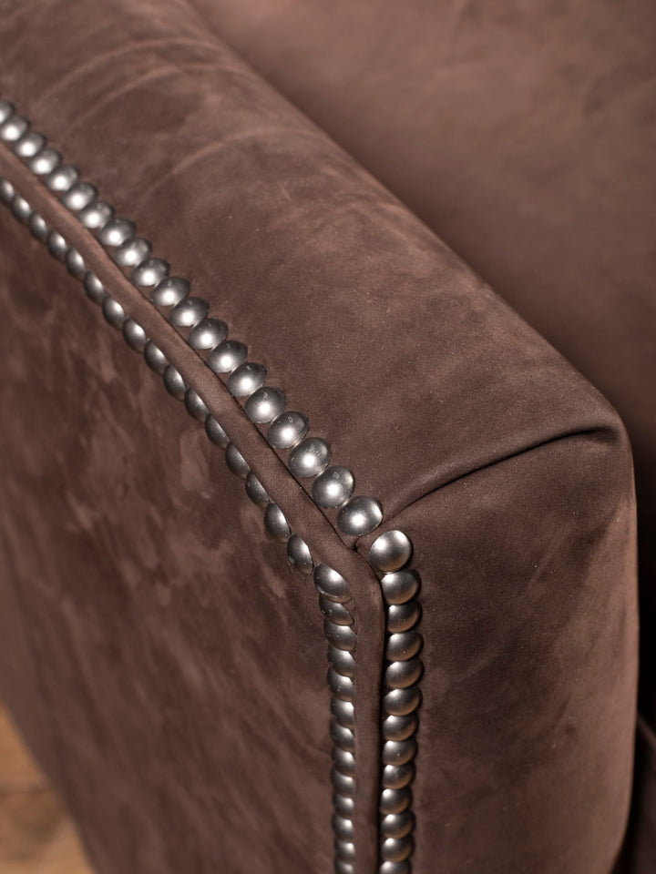 Close up of brown leather recliner arm with silver nailheads