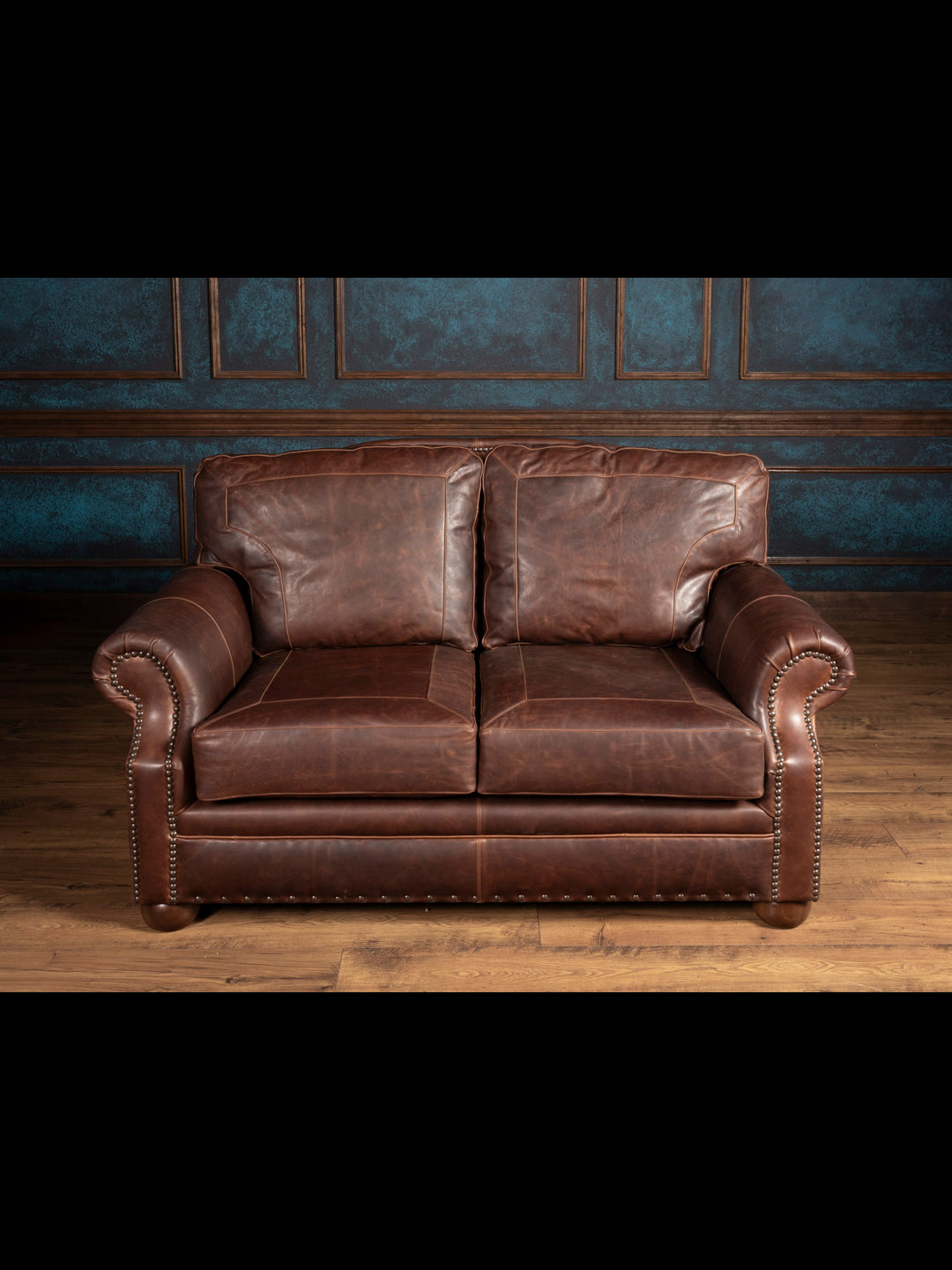 Brown leather sofa against a blue paneled wall.