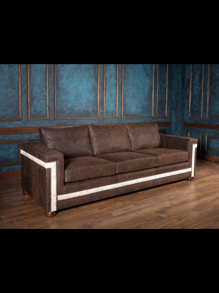 Angled view of handcrafted Western leather sofa with gray cowhide panels and architectural lines