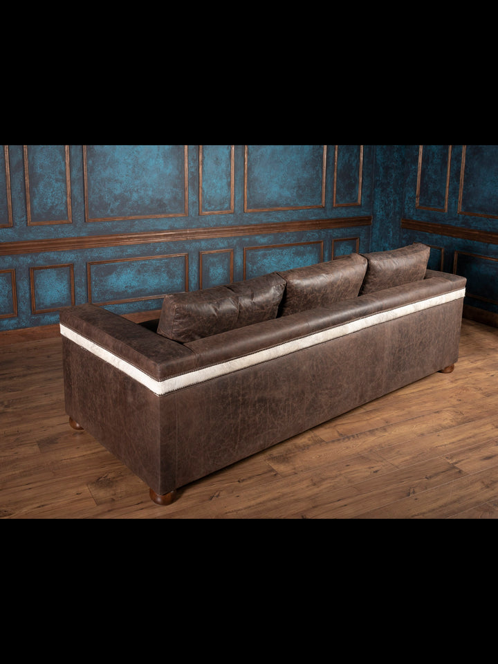 Back view of Western cowhide and leather sofa with hand-placed nailheads and custom gray cowhide panels
