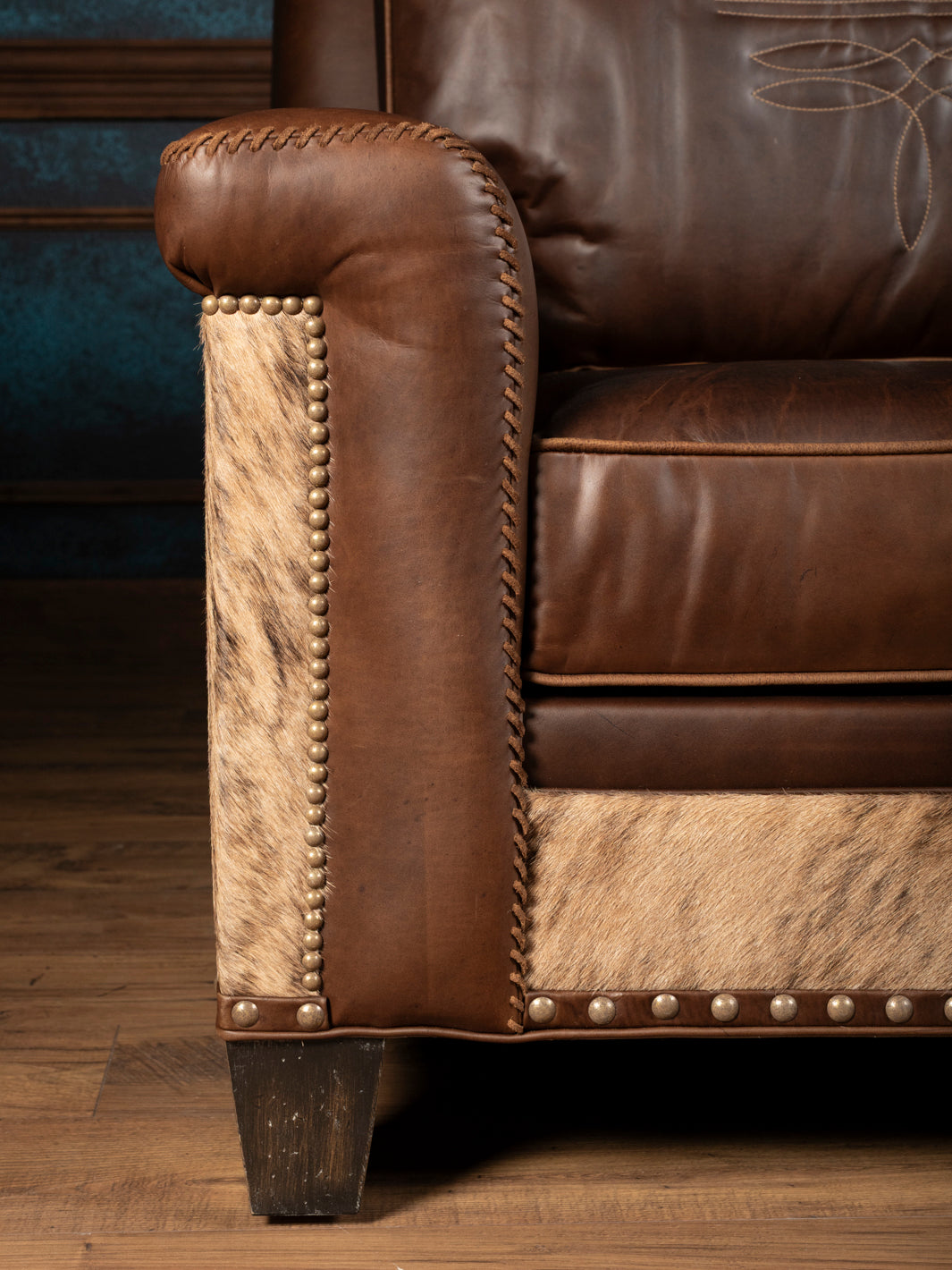 Heritage Whipstitch leather sofa showing a boot-stitched back cushion, whipstitched arm and natural cowhide side panel.