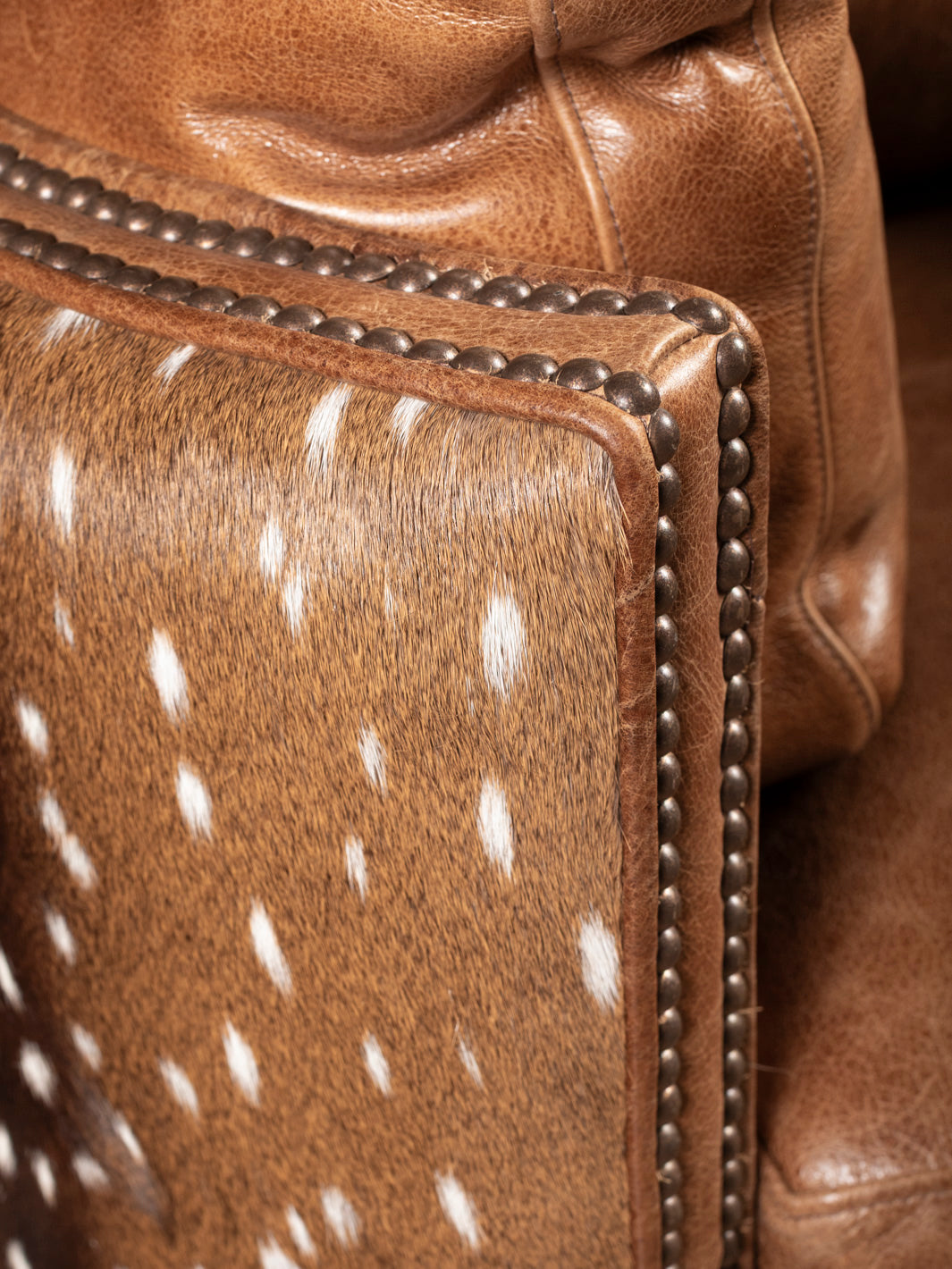 Side panel close-up showcasing axis deer hide on recliner Axis hide texture and trim detailing on Western swivel leather recliner.