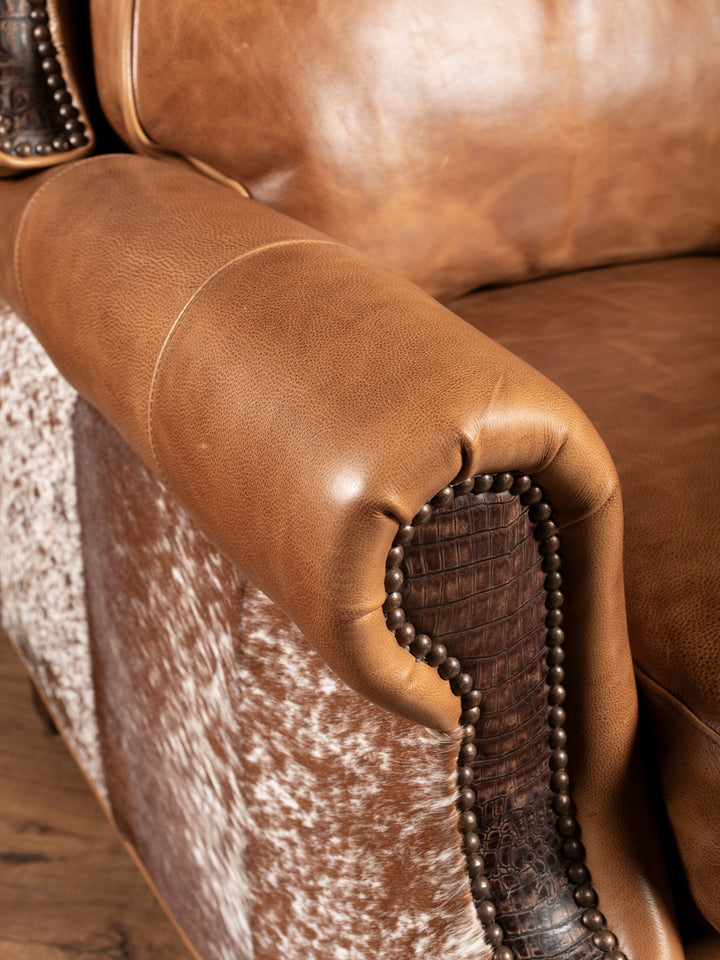 Up-close shot of rolled arm silhouette featuring crocodile-embossed leather panels, smooth full-grain saddle leather, and hair-on-hide detailing.