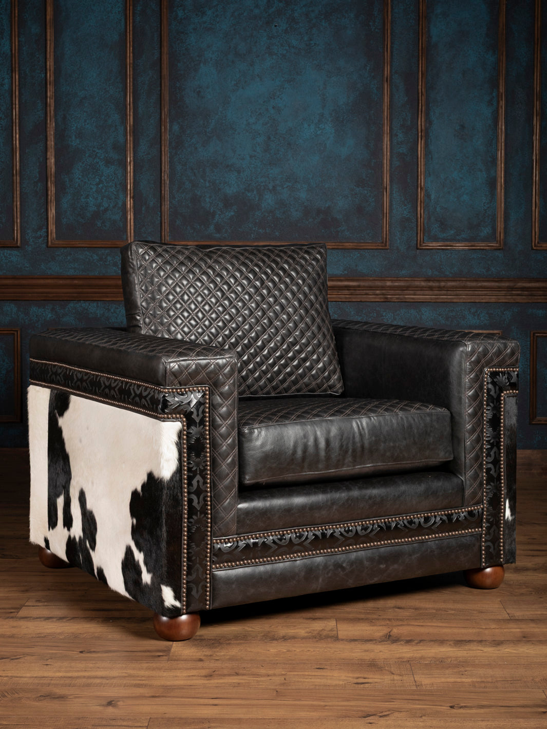 Black leather armchair with cowhide pattern on a wooden floor and dark blue wall background