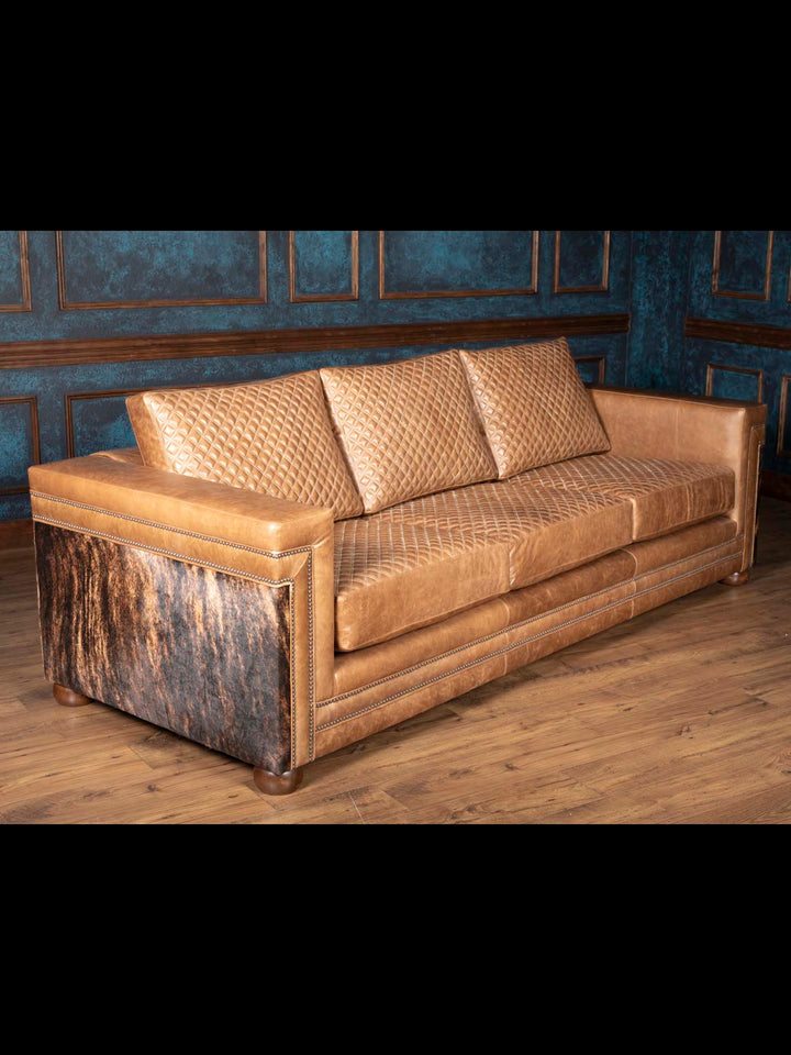 Side view of tan leather and cowhide Western sofa with diamond quilted cushions and rounded wood feet