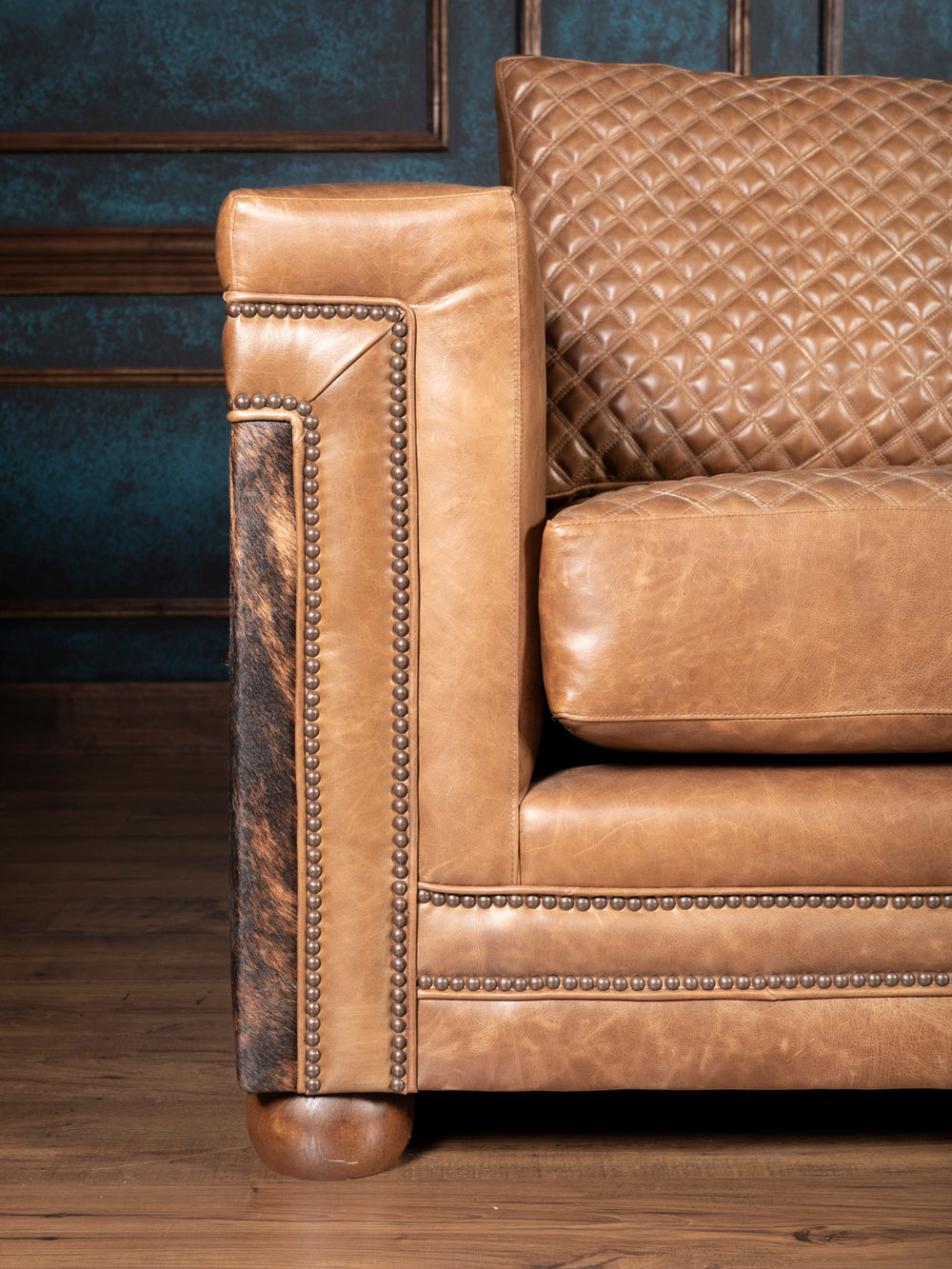 Close up of arm on brown leather sofa with nailhead trim and genuine hair on hide panels