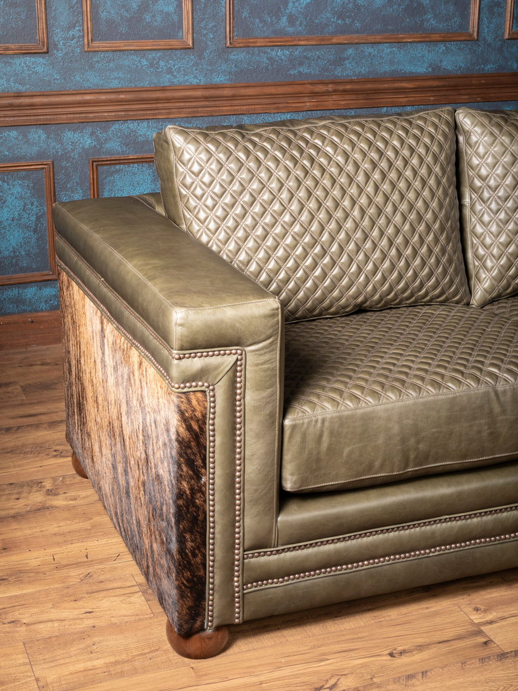 Angled view of Green leather and cowhide Western sofa with quilted cushions