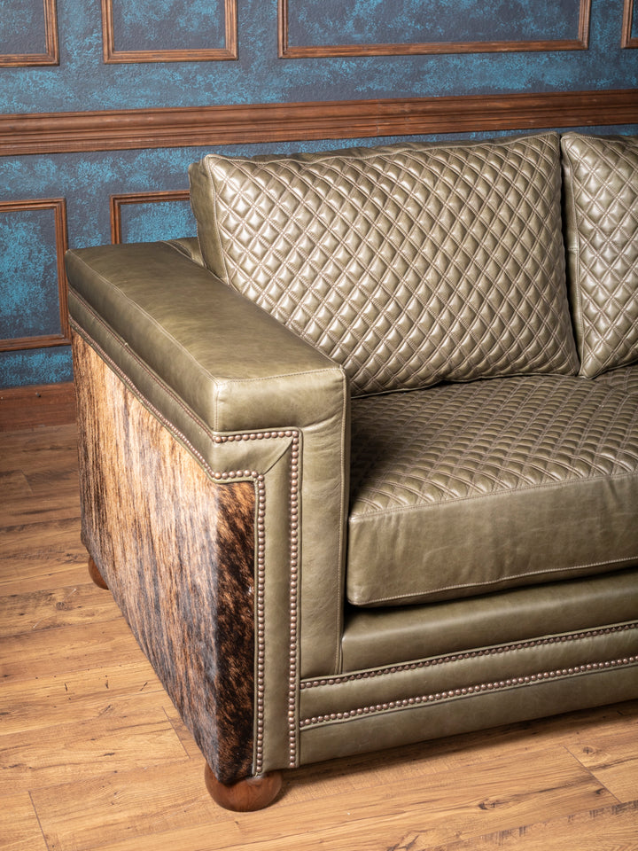 Angled view of Green leather and cowhide Western sofa with quilted cushions