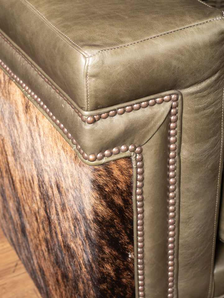 Detail of green leather arm and cowhide panel with nailhead trim on sofa