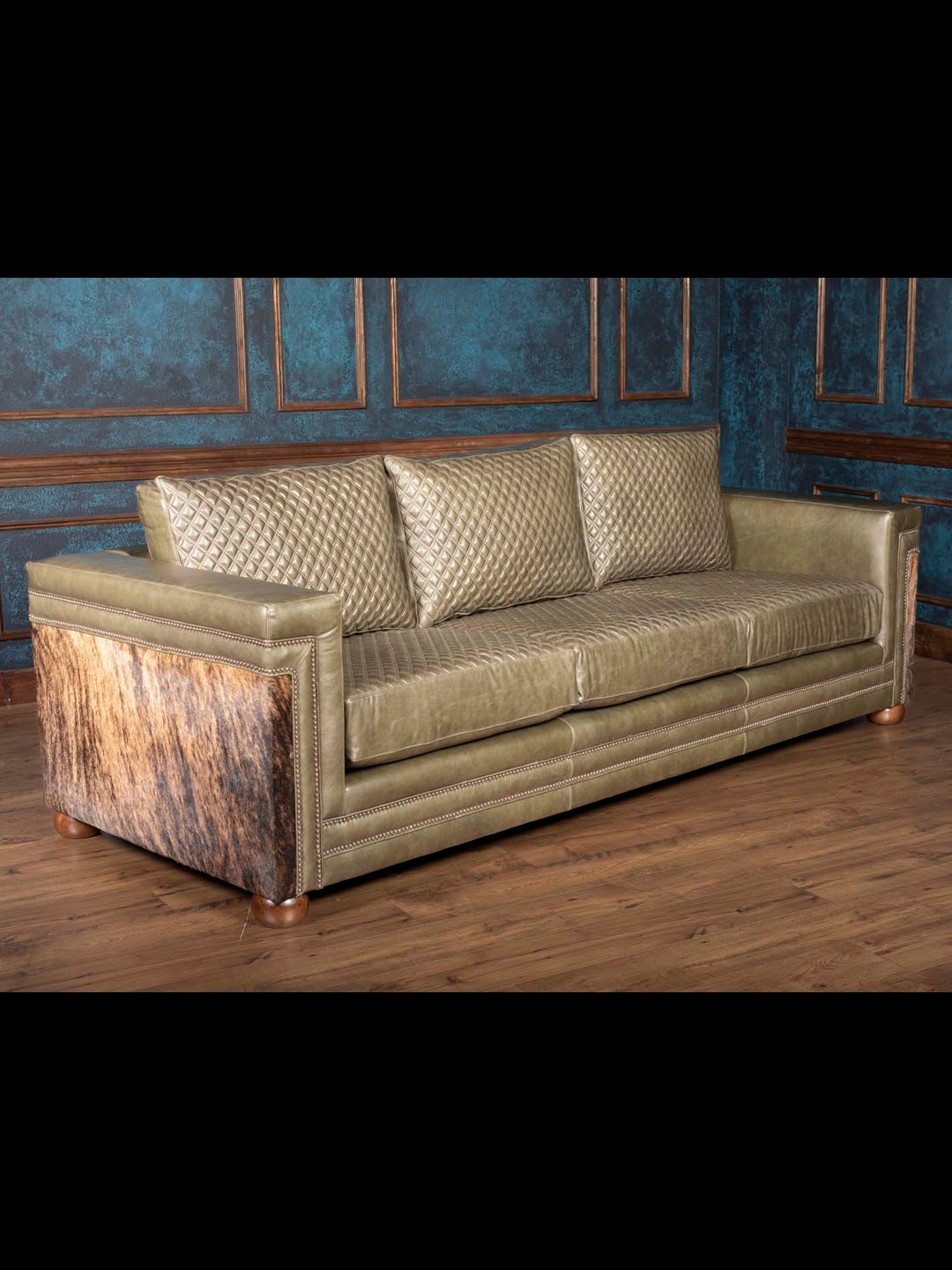 Side view of Green leather sofa with cowhide sides and Western nailhead trim
