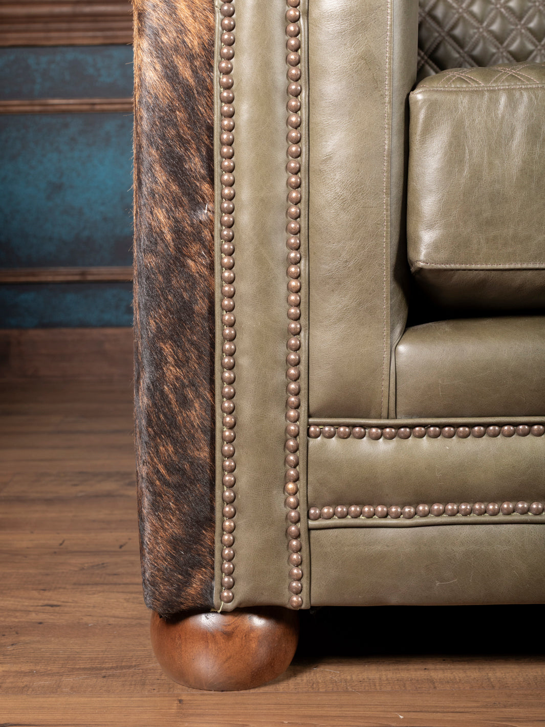 Trim detail on green leather and cowhide Western sofa showing nailhead accents