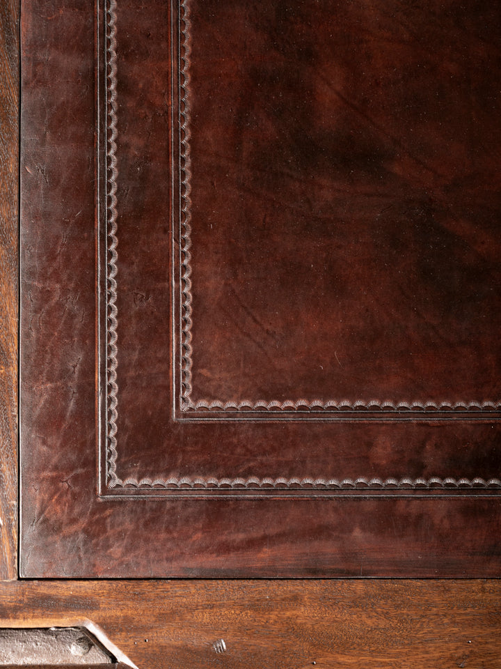 Close-up of a brown leather-bound book corner with embossed design.