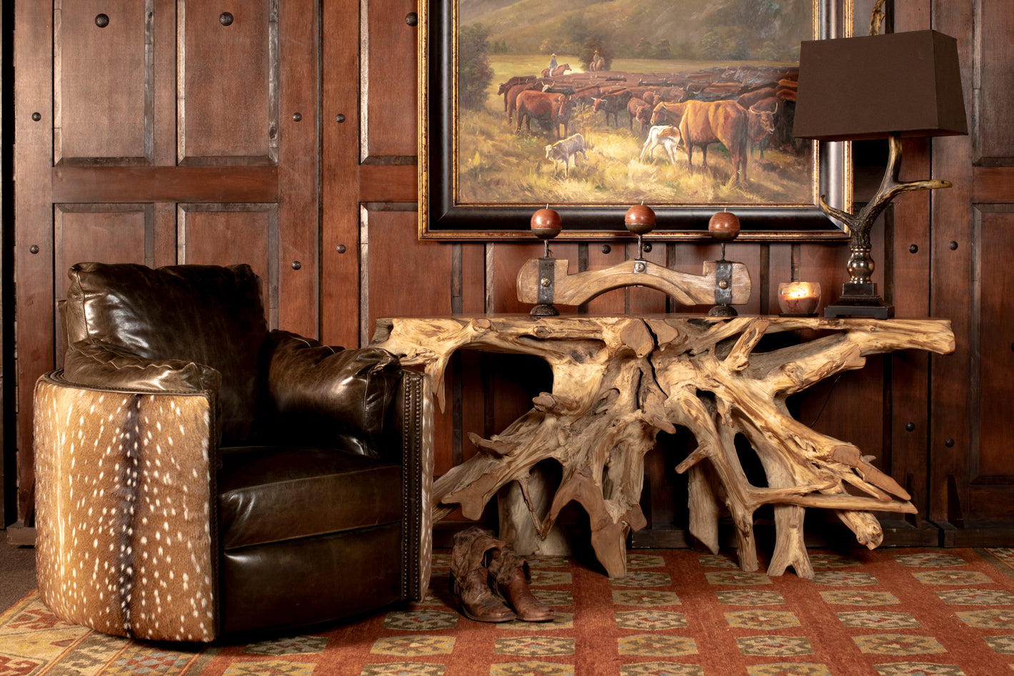 Layered Western vignette with distressed leather recliner, axis hide ottoman, reclaimed driftwood console, and oil painting
