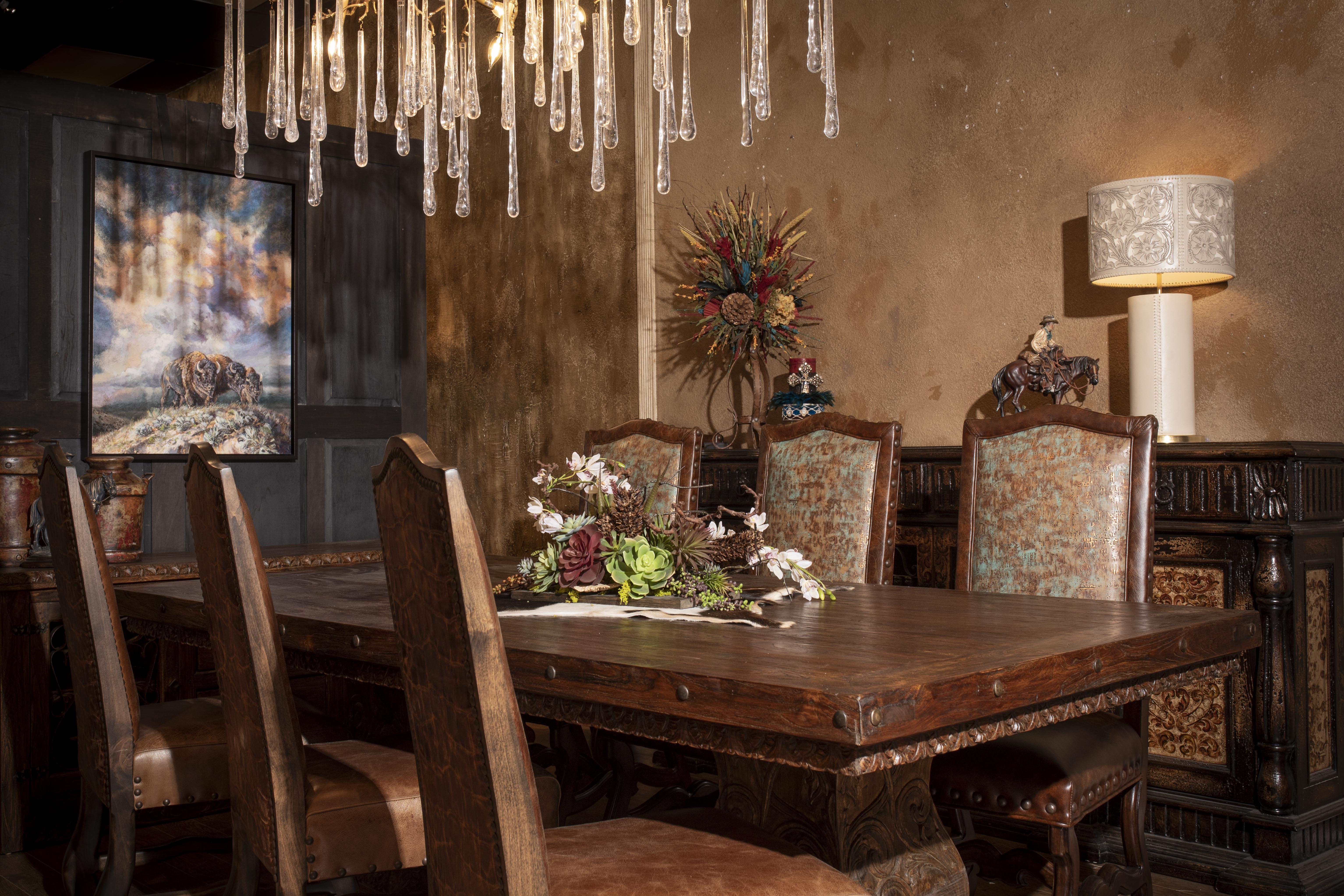 Western dining room with hand-carved reclaimed wood table, tapestry and leather dining chairs, and a crystal drop chandelier