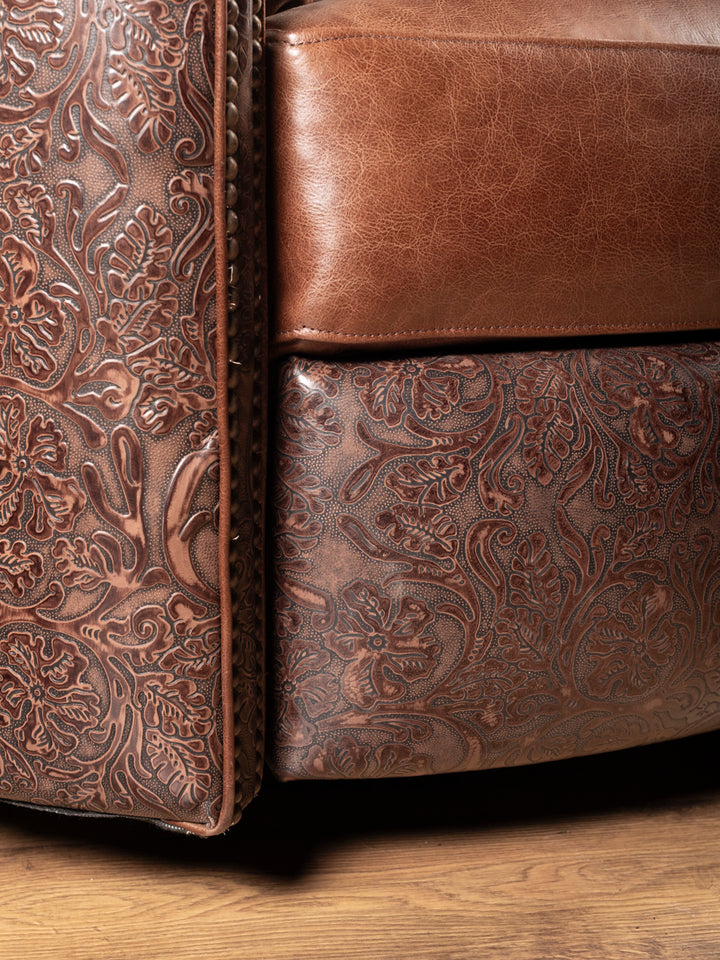 Zoomed view of handcrafted floral tooled leather and full-grain saddle leather on chair base and arm.