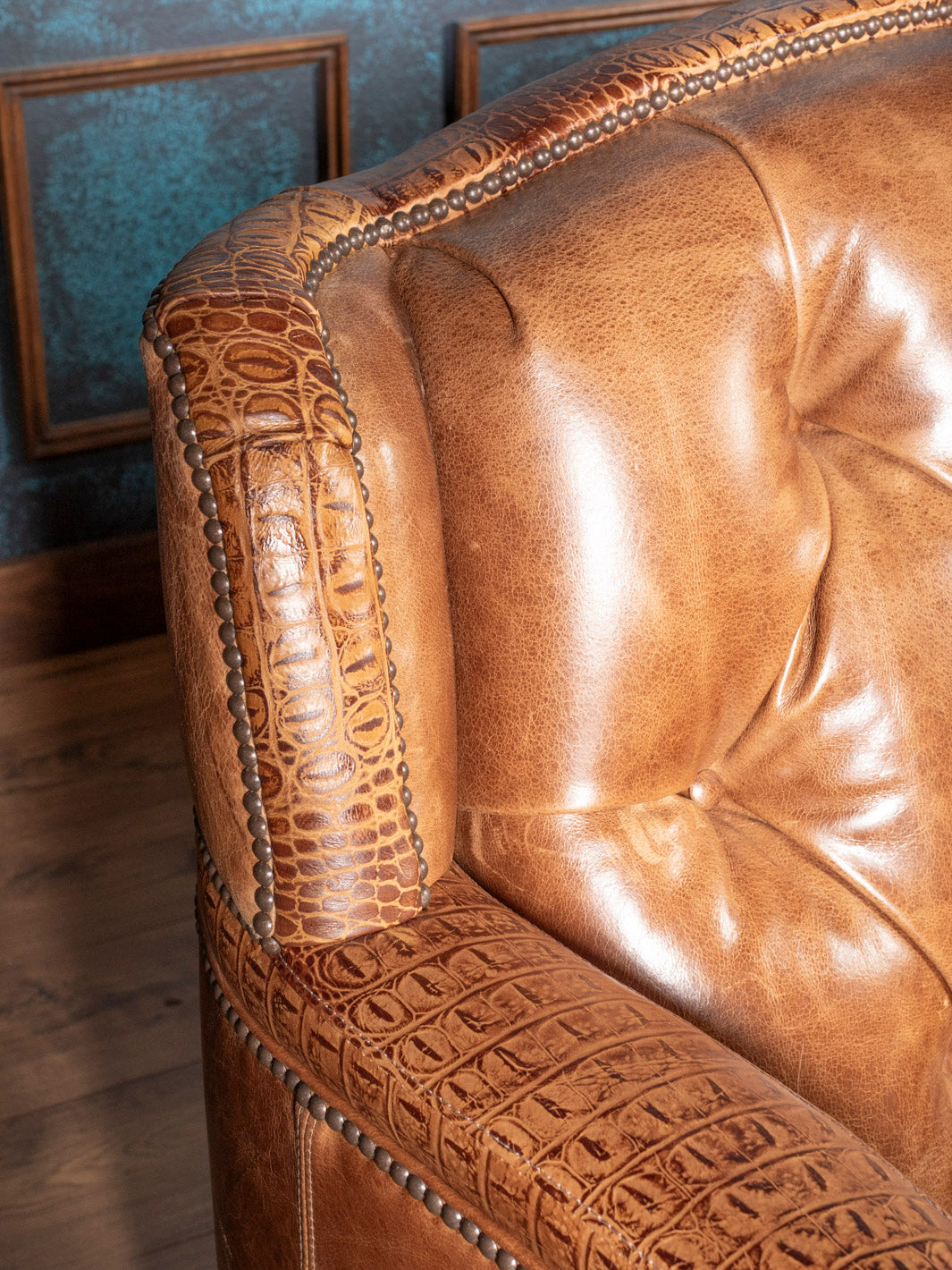 Close-up of a brown leather sofa with croc and nailhead detailing