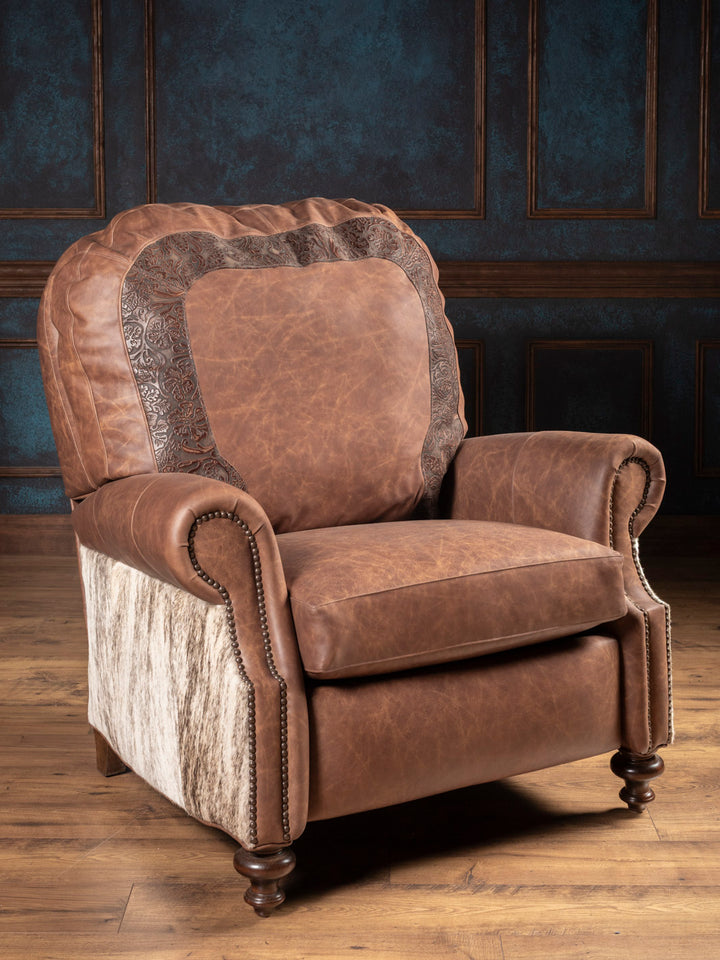 Brown leather recliner chair with patterned armrests in a room with wooden flooring and dark paneled walls.