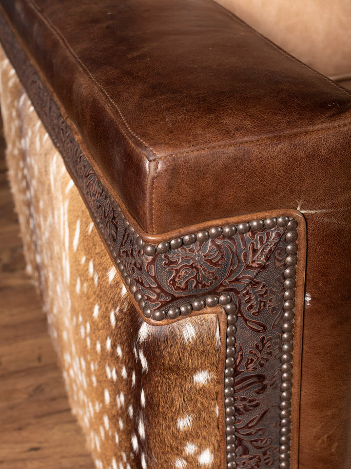 Close up image of brown leather arm with embossed leather and axis hide inlay.