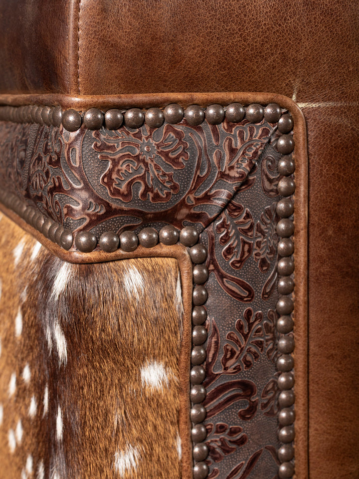 Close-up of a leather product with intricate floral embossing and metal studs.