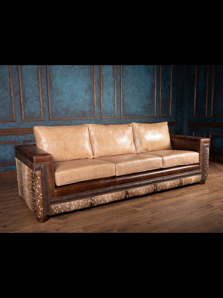 Sandstone Axis Leather Sofa in tan buffalo leather with axis deer hide panels and nailhead trim in a rustic Western living room