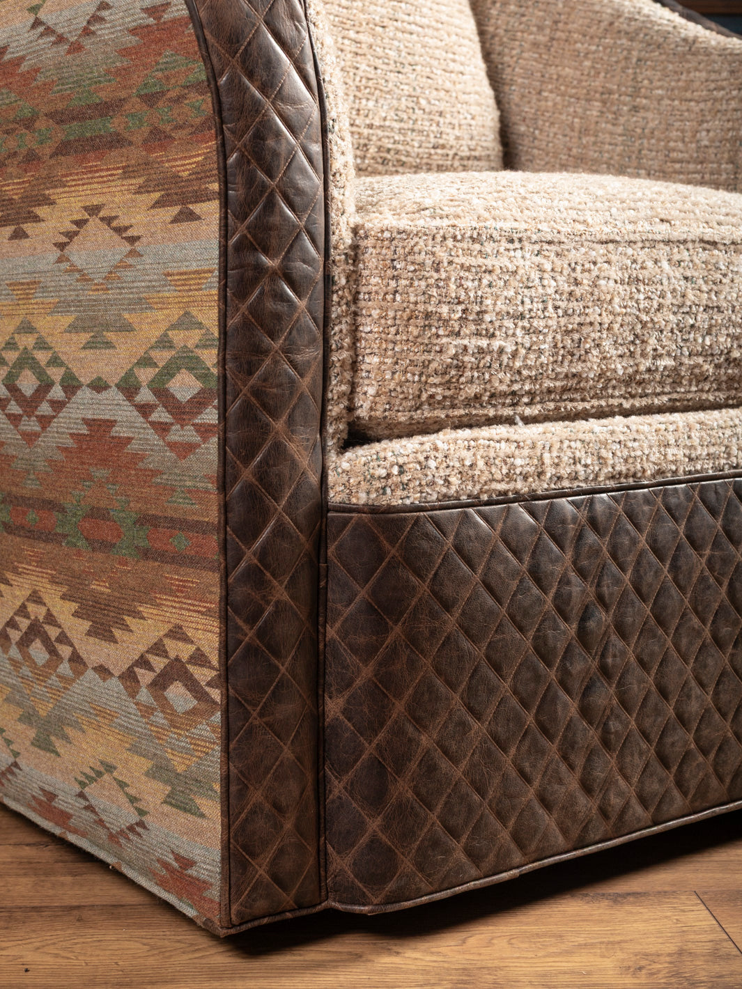 Lower front detail: Hand-quilted leather-look trim on boucle swivel chair base
