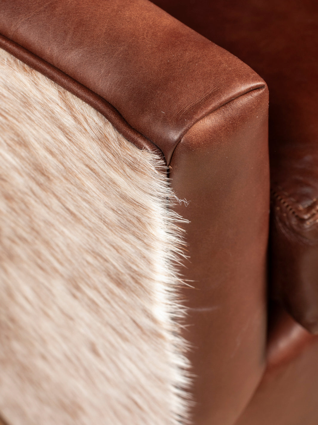 Close-up of a brown leather armrest with a cowhide pattern.