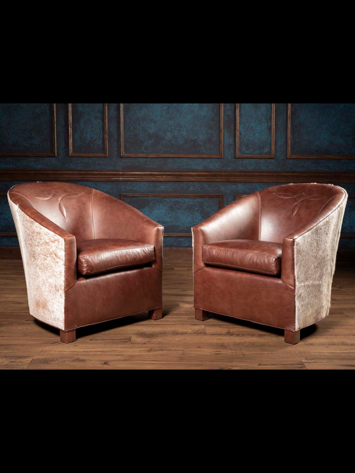 Two Western speckled chocolate brown leather accent chairs styled in rustic living room setting