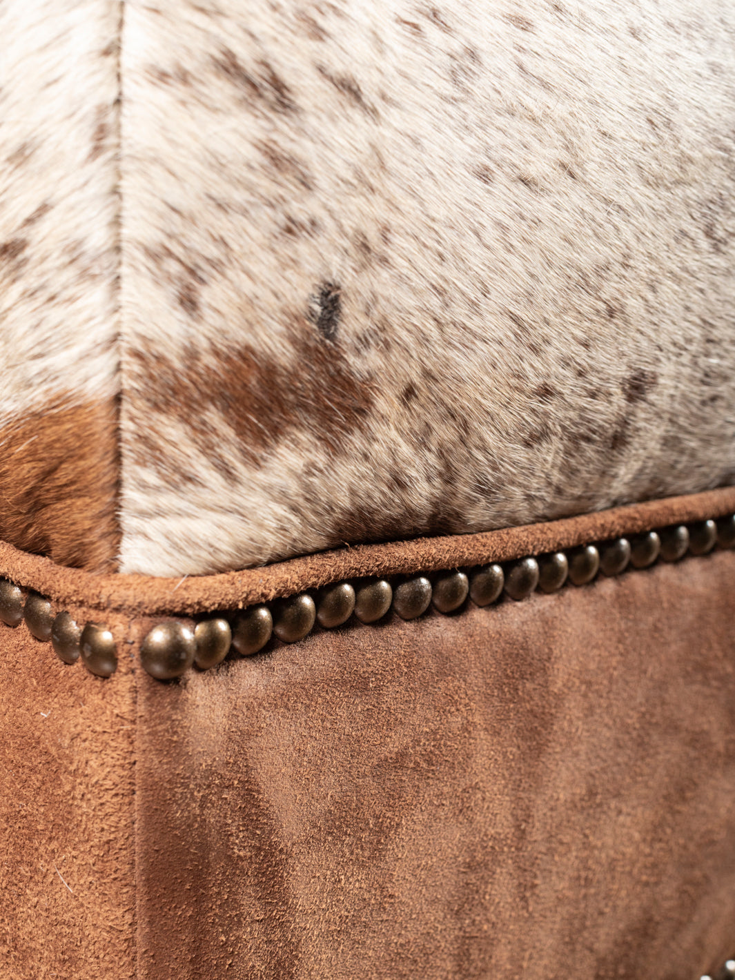 Brown suede side panel with nailhead trim on cowhide and leather rustic ottoman