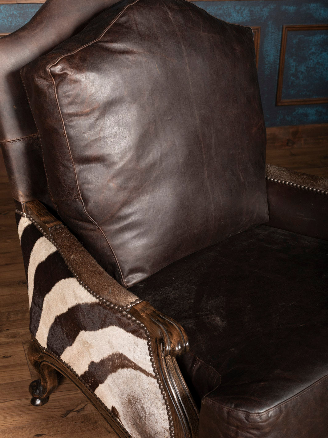 Side profile of zebra leather chair showing striped hide and carved wood frame