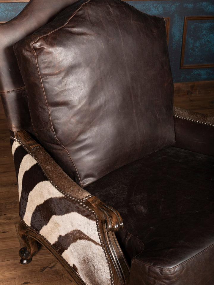 Side profile of zebra leather chair showing striped hide and carved wood frame