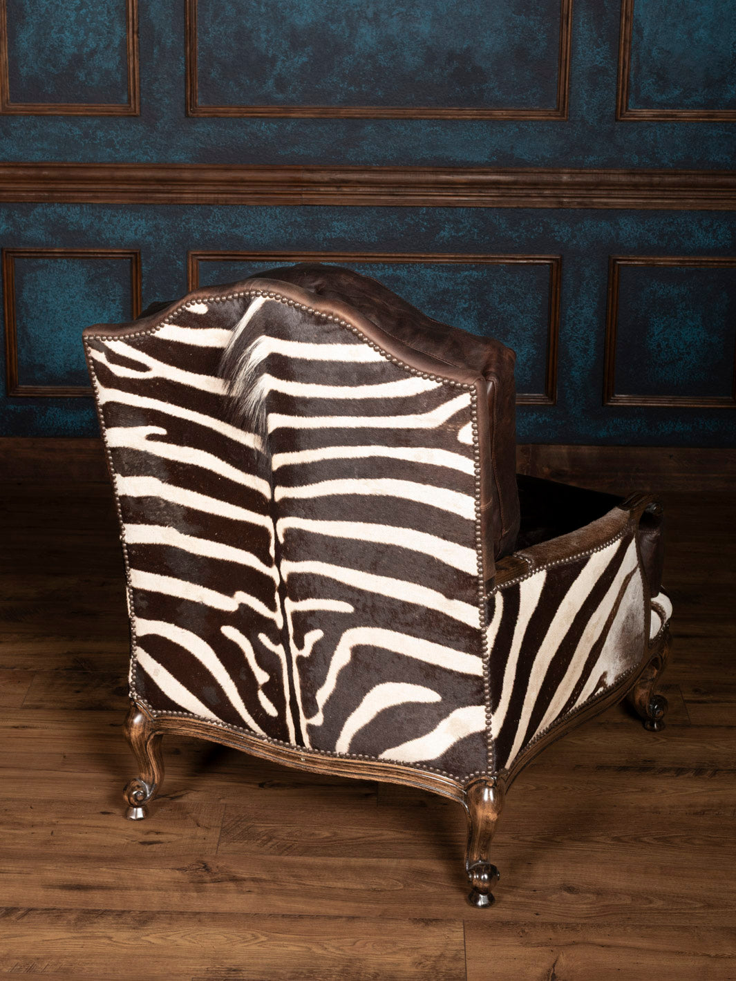 Chair with zebra pattern upholstery in a room with dark wood paneling.
