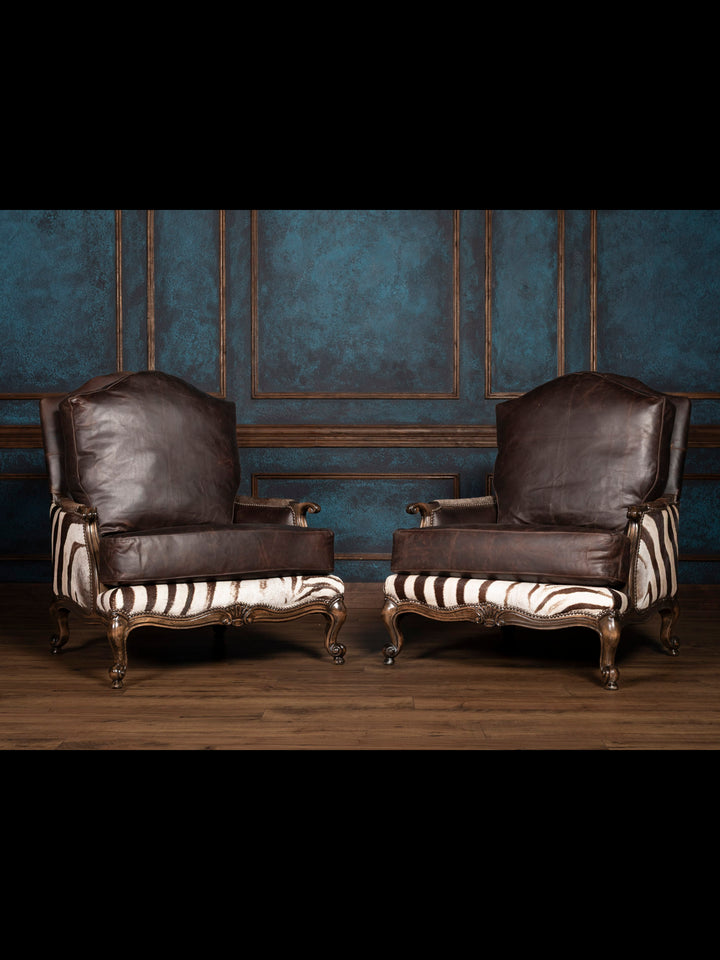 Pair of ornate armchairs with zebra hide details and dark leather.