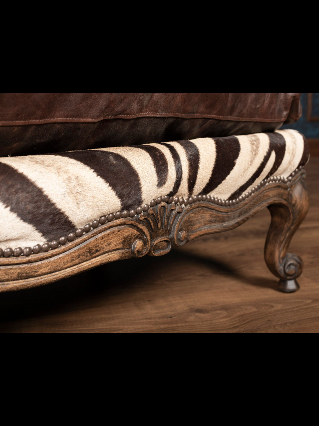 Close-up of genuine zebra hide and hand-applied nailhead trim on exotic leather ottoman