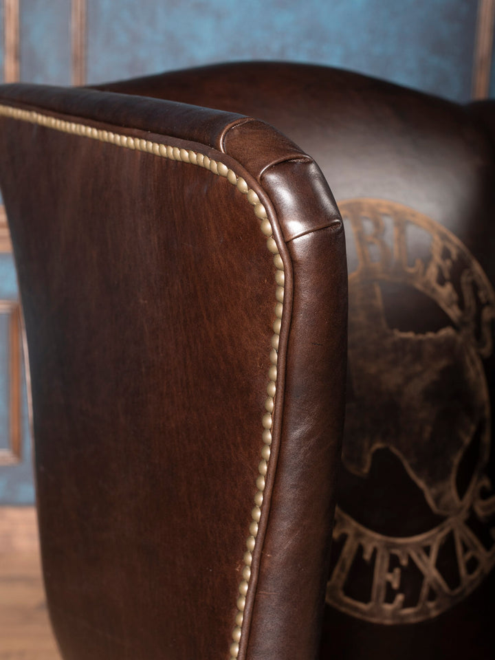 Side profile of luxury Texas Legacy Wingback Chair featuring nailhead trim and rich brown leather upholstery