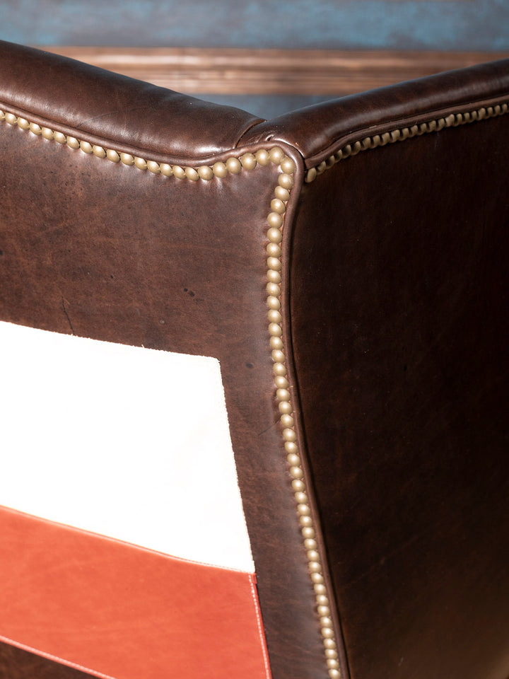 Close-up of a brown leather chair with visible nailhead detail.