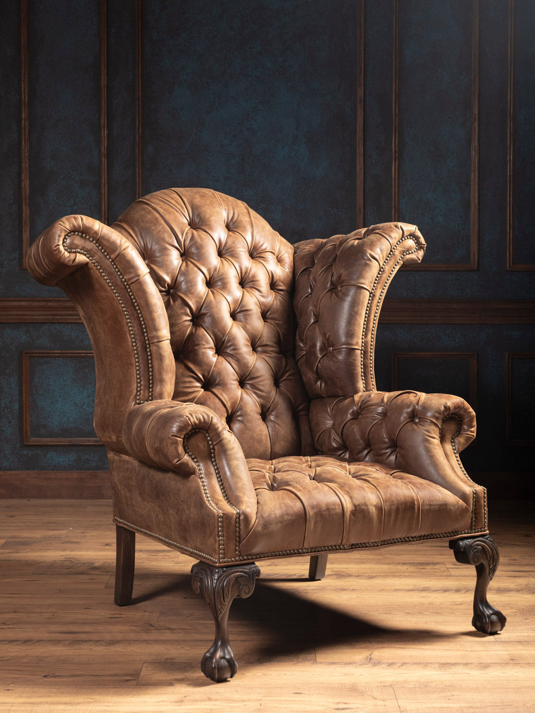 Front view of tufted distressed tobacco leather wingback chair with rolled arms and carved claw-foot legs