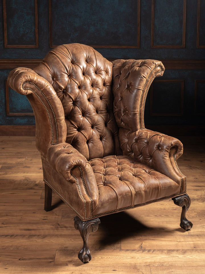 Side angle of handcrafted tobacco brown leather chair showcasing button tufting and nailhead trim