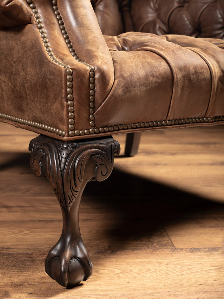 Back view of wingback chair in distressed leather with smooth curved frame and claw-foot base