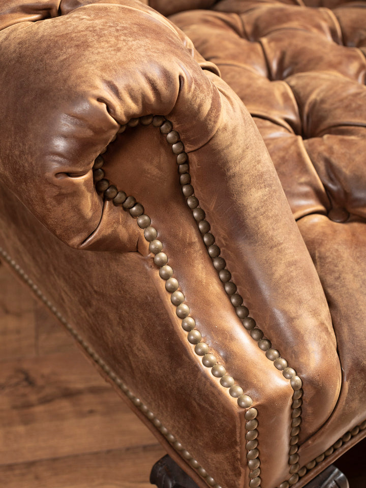 Close-up of deep tufted seat and armrest on Western-style distressed leather accent chair