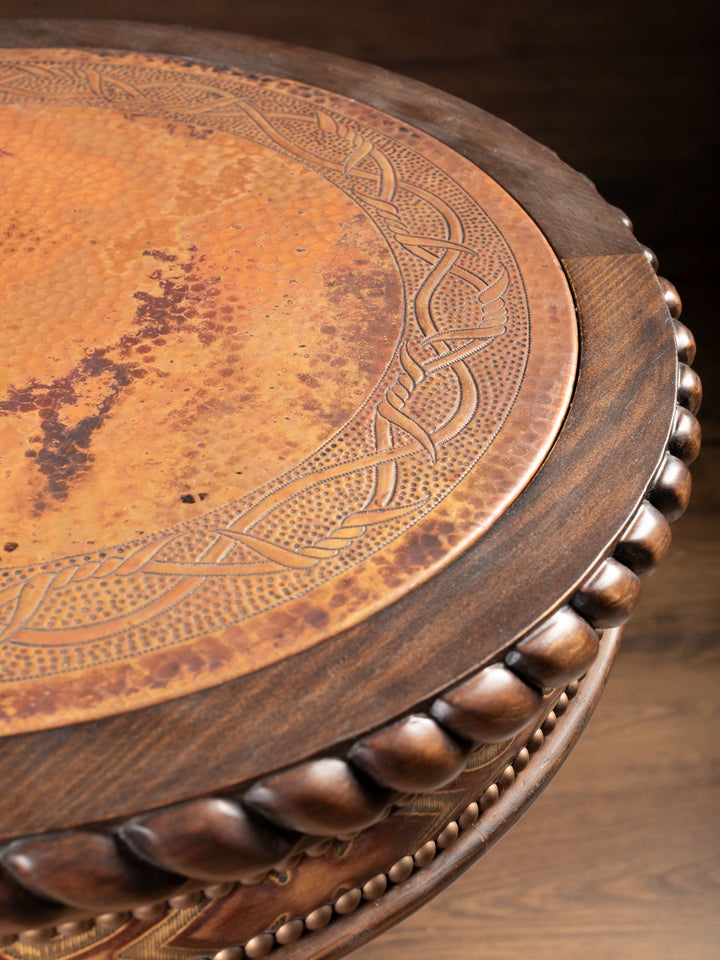 Close-up of hand-carved copper inlay tabletop with detailed hammered texture and carved wood edging on rustic western end table.