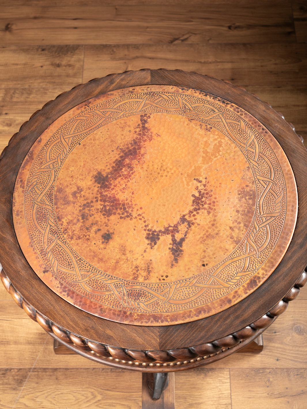 Top-down view of round copper inlay tabletop featuring hand-carved patterns and rustic aged finish.