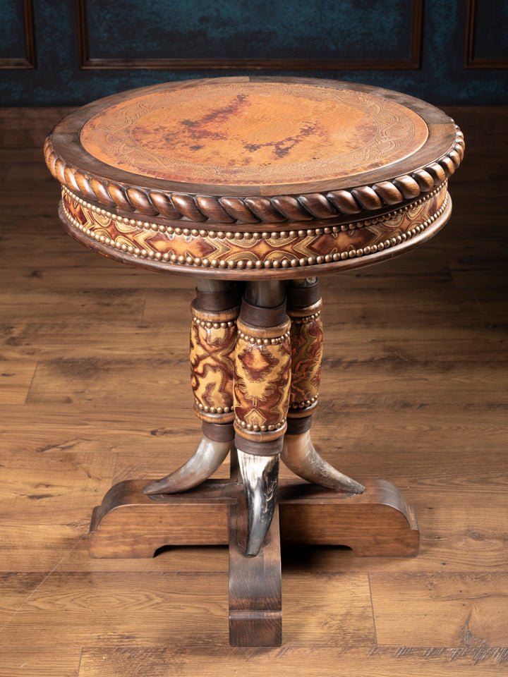 Angled view of rustic western end table showing copper inlay top, carved wood trim, and steer horn pedestal with embossed leather.